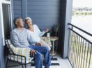 Um casal de idosos está feliz em uma varanda, em alusão ao momento da aposentadoria