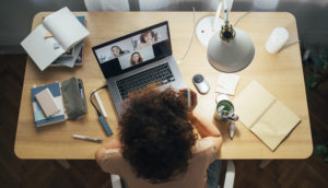 Mesa com pessoa em home office, com laptop e objetos de escritório