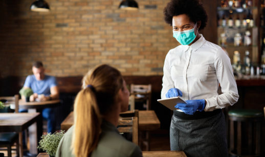 Garçons atende cliente com máscara