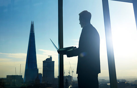 Executivo com laptop em mãos olhando para paisagem de cidade