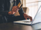 Mulher com laptop e cartão de crédito na mão, alusivo aos benefícios dos cartões de crédito Safra