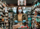 mulher com carrinho de supermercados fazendo compras de mascara