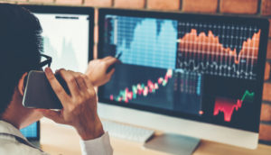 Mãos apontando para tela de computador com home broker