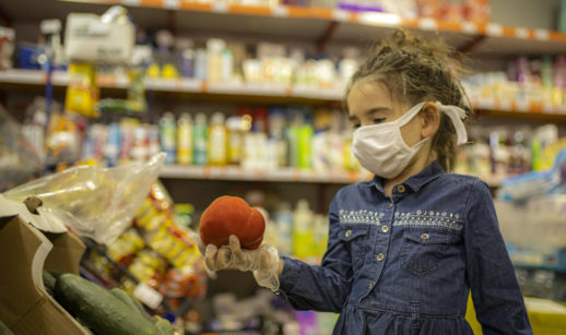 menina no mercado de máscara e luvas praticando o consumo consciente