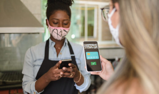 Mulheres de máscara fazendo transferência de dinheiro pelo celular