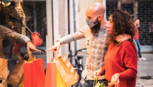 Casal de máscaras de proteção olhando vitrine feliz fazendo compras