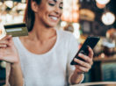 mulher com celular e cartão do banco