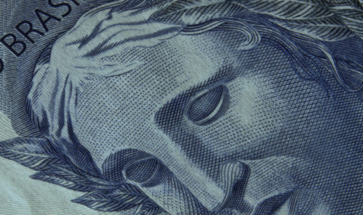 Detalhe de um rosto na cédula do Real com a palavra "Brasil" em destaque. PIB per capita