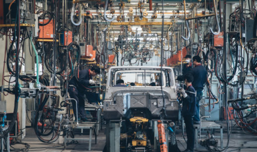 Fábrica de carros com funcionários trabalhando em carroceria