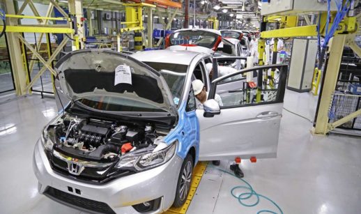 Homem dentro de carro em linha de produção de fábrica da montadora Honda