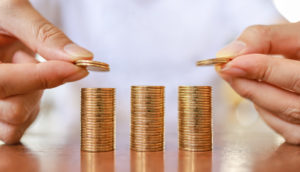 Pessoa empilhando moedas com as duas mãos, alusivo a dividendos de ações