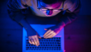 Pessoa em frente a notebook vista de cima e se precavendo de crimes virtuais