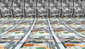 Impressão de dólares em máquina, alusiva ao movimento de inflação acelerada, com reflação