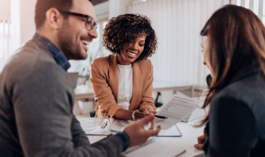 três pessoas sorridentes em uma mesa com papéis