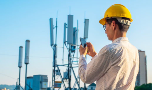 Homem com celular diante de antenas
