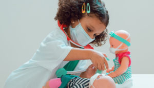 Criança brinca com bonecas de máscaras