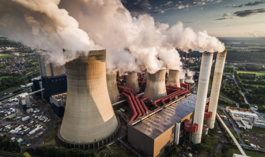 Chaminés de fábricas soltando fumaça, alusivo às emissões globais