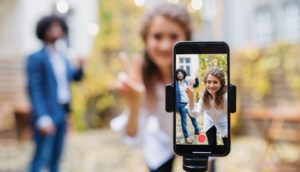 Casal contracenando em frente ao celular, alusivo aos downloads do aplicativo de vídeos curtos Tik Tok