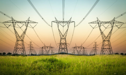 Torres de energia elétrica em campo verde com pôr do sol
