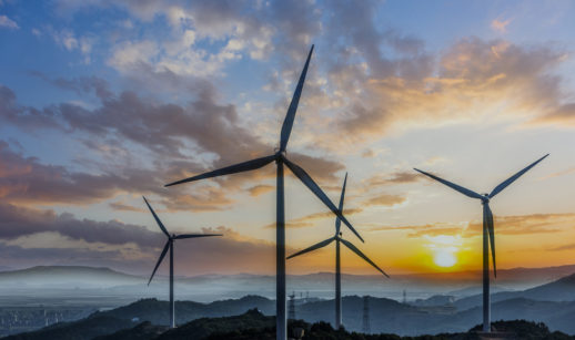 Campo de energia eólica com torres com o pôr do sol de fundo, alusivo à empresa Aeris, com ticker de ações AERI3
