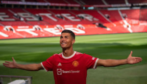 Cristiano Ronaldo, que passou Lionel Messi como mais bem pago, sorrindo de braços abertos e olhando para cima em Old Trafford, estádio do Manchester United