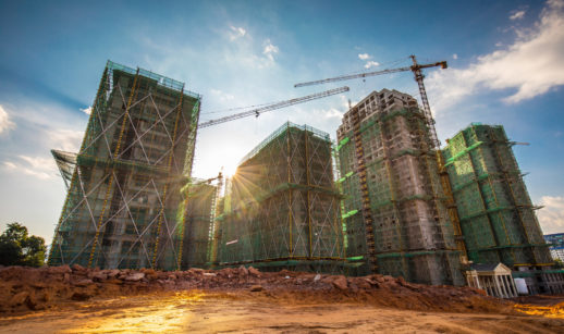 Quatro torres em construção ao fundo com terreno aberto na frente, alusivo à Evergrande