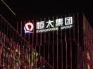 Fachada de prédio da Evergrande com logo iluminado a noite