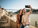 Casal de turistas tirando selfie na cidade do Porto, em Portugal, sem máscaras e sorrindo