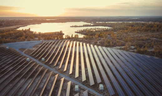 Painéis de energia solar enfileirados e iluminados com lago ao lado