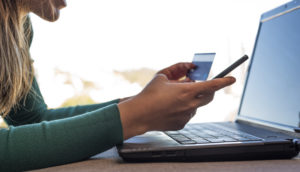 Mulher com celular e cartão do banco