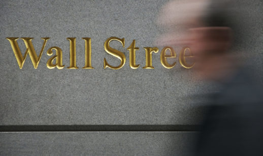 Foto de parede com destaque para Wall Street e pessoa passando em frente borrada, alusivo à carteira Safra Top 10 BDRs