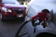Close de bomba de combustível abastecendo carro com um segundo atrás em segunda perspectiva, alusivo ao IPCA de outubro