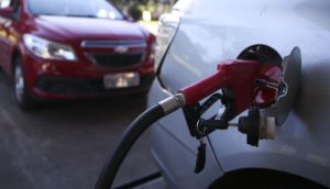 Close de bomba de combustível abastecendo carro com um segundo atrás em segunda perspectiva, alusivo ao IPCA de outubro