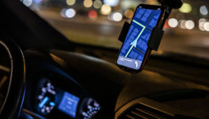 Foto de dentro de carro à noite com o aplicativo da Uber ligado