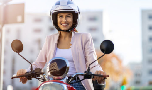 Mulher sorrindo de capacete em cima de motocicleta, alusivo às vendas de motos no Brasil em novembro