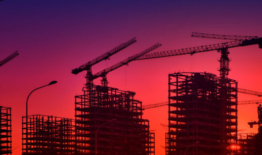Silhueta de esqueletos de prédios e guindastes com pôr do sol ao fundo, alusivo ao default da Evergrande