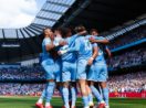 Elenco do Manchester City abraçado no meio do gramado de seu estádio. Clube é o líder entre os times com elencos mais valiosos do mundo