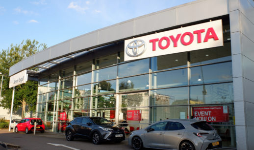 Fachada de concessionária da Toyota com carros na frente pela manhã
