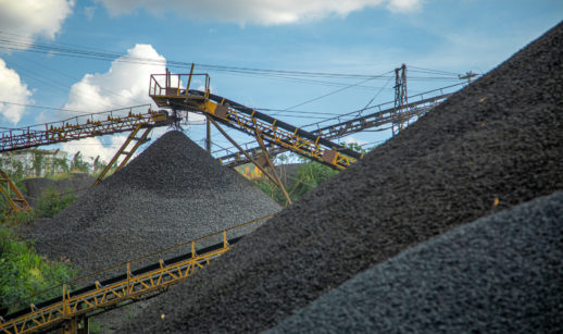 Montanhas de minério de ferro com máquinas amarelas trabalhando, alusivo à produção da Vale