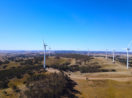 Aérea de parque eólico em meio ao campo, alusivo aos parques da AES Brasil