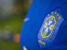 Detalhe da camisa azul da seleção brasileira, com close no escudo da CBF, alusivo aos clubes brasileiros de futebol, que tiveram lucro nos últimos 5 anos