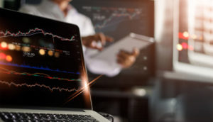 Laptop com tela com números e gráficos de ações, alusivo às top picks que têm a Energisa entre elas nessa semana