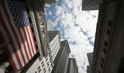 Perspectiva de baixo para cima de prédios de Wall Street, nos EUA, em dia ensolarado