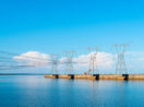 Torres de transmissão de energia com céu e rio azuis, alusivo às ações do setor com foco em dividendos para abril