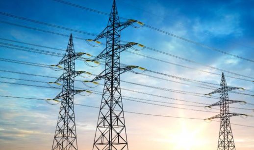 Perspectiva de baixo para cima de torres de transmissão de energia com céu azul e amarelo, alusivo à Neoenergia