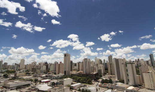 Paisagem de prédios e casas com céu azul e nuvens brancas no fundo, alusivo ao aluguel residencial