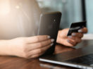Close de mãos com celular e cartão de crédito, alusivo à segurança digital dos bancos