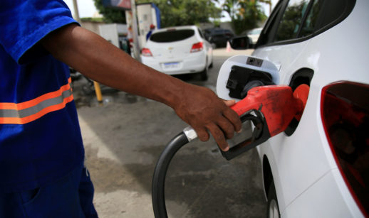 Close de mão de frentista abastecendo carro branco, alusivo à alta dos preços com a prévia da inflação de abril