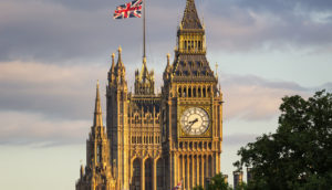 Parlamento do Reino Unido, para onde Elon Musk foi convidado a explicar transação com o Twitter, com destaque para bandeira britânica no alto e árvore à frente em primeiro plano