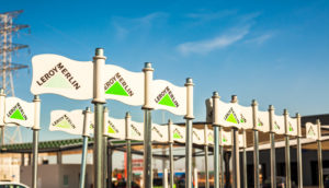 Bandeirinhas da Leroy Merlin em carrinhos de uma de suas lojas com céu azul ao fundo